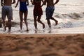 Four friends running into the water on a sandy beach, Silhouette Royalty Free Stock Photo