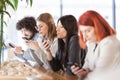 Four friends sitting at a cafe bar looking at phones Royalty Free Stock Photo