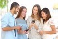 Four friends watching social media in a smart phone