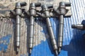 Four fuel injectors are lying on a blue work table in an auto repair shop