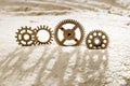 Four gears in the sand cast a shadow on the sand Royalty Free Stock Photo