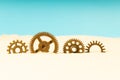 Four gears in the sand, yellow sand and blue background Royalty Free Stock Photo