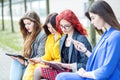 Four girls with gadgets are sitting on the bench. The concept of the Internet, social networks, study and lifestyle Royalty Free Stock Photo