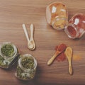 Four glass jar with spices and four wooden spoon on the table