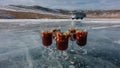 Four glass mugs with mulled wine are standing on a frozen lake.