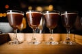 Four glasses with chocolate-colored alcoholic cocktails and white foam