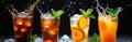 Four glasses with cold drinks splash, ice cubes, mint and citrus slices on black background. Refreshing and orange beverages with Royalty Free Stock Photo
