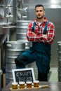 Four glasses of craft beer on beer sampler tray and brewer standing in background