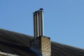 Four gray pipes on a brown brick chimney on the slate roof