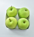 Four green apples in a cardboard box