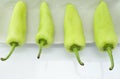 Four green peppers in composition on white plate Royalty Free Stock Photo