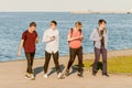 Four guys teenagers walk along the embankment on a summer day. Happy Faces