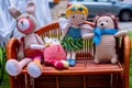 Four handmade knitted toys on wicker shelf