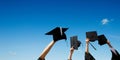 Four hands holding graduation hats against sky Royalty Free Stock Photo