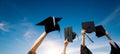 Four hands holding graduation hats against sky Royalty Free Stock Photo