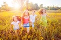 Four happy beautiful children running playing moving together in the beautiful summer day.