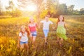 Four happy beautiful children running playing moving together in the beautiful summer day.