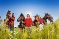 Four happy equestrians walking with their horses Royalty Free Stock Photo