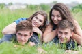 Four happy friends lying together on green grass outdoors Royalty Free Stock Photo