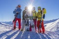 Four happy friends snowboarders and skiers are having fun on ski slope with ski and snowboards in sunny day. Royalty Free Stock Photo