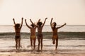 Four happy girls runs at sunset sea beach Royalty Free Stock Photo