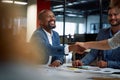 Four happy multiracial business people in businesswear shaking hands during meeting in office