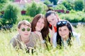 Four happy smiling teen friends in green grass outdoors Royalty Free Stock Photo