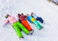 Four happy snowboarders lying in a row