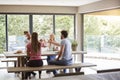 Four happy young adult friends celebrating raise wine glasses during a dinner party, back view