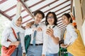 four high school students look together and point to the mobile phone screen