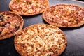 Four homemade different pizzas on dark wooden background