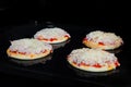 Four homemade mini pizzas baking on tray in electric oven