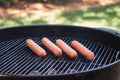 Four hot dogs grilling outside on a charcoal bbq grill Royalty Free Stock Photo