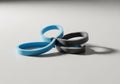 Four interlinked silicone wristbands, two blue and two black, are Royalty Free Stock Photo