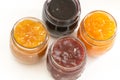 Four jars of different jam on white background, top view