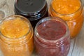 Four jars of different jam on wooden background, top view