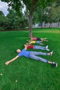 Four joyful and happy children lie in a row in the park on the green grass Royalty Free Stock Photo