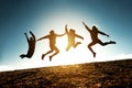 Four jumping silhouettes friends against sun