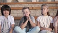 Four kids looking bored and overtired seating on a bench.