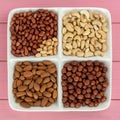 Four kinds of nuts in four compartments on a pink background: Royalty Free Stock Photo