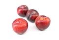 Four large red plums with little yellow dots on white background Royalty Free Stock Photo