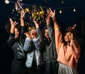 Four laughing females throw confetti in the air at night Royalty Free Stock Photo