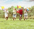 Four laughing kids running on green lawn