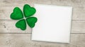 Four leaf clover and greeting card on wood