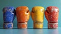 Four leather boxing gloves, each in different bold colors, standing on a teal surface. Concept of diversity in sports Royalty Free Stock Photo