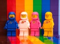 Four Lego astronaut minifigures standing against a rainbow backdrop