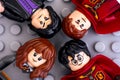 Four Lego Harry Potter minifigures - Harry Potter, Hermione Granger, Severus Snape and Oliver Wood on gray background