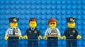 Four Lego police officers standing in a row against blue Lego baseplate
