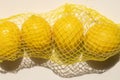 four lemons inside yellow plastic net Royalty Free Stock Photo
