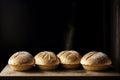 Four loaves of bread on a wooden board with a black background.